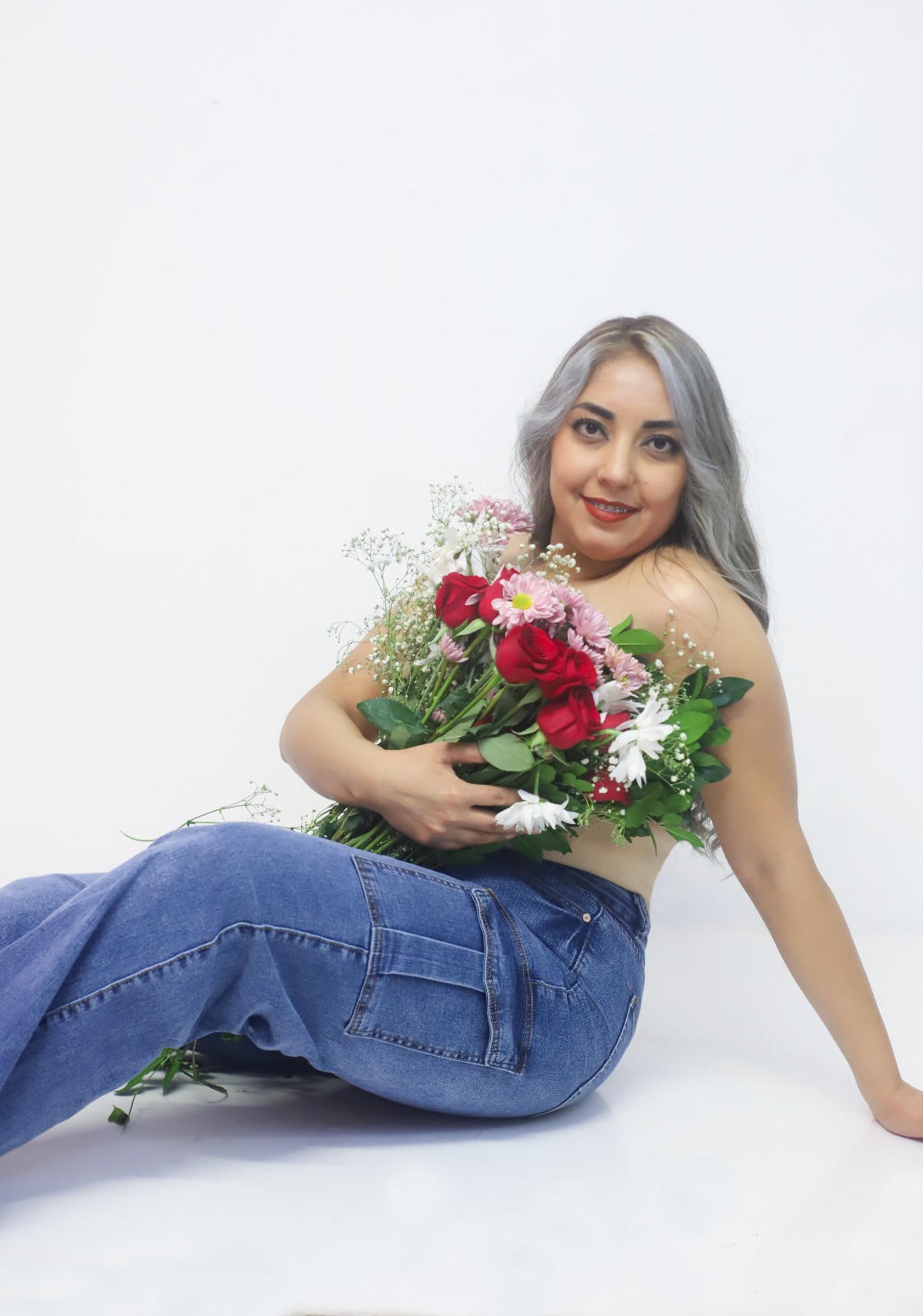 Retrato de estudio de una mujer recostada con un ramo de flores.