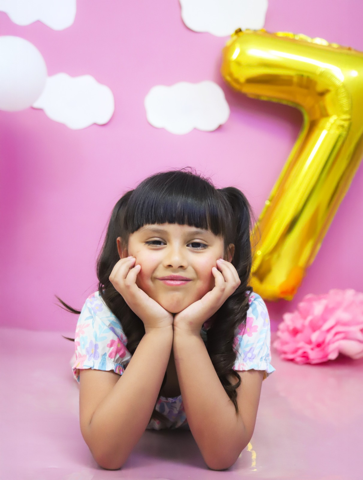 Retrato de una niña con decoración rosa y el globo número siete.