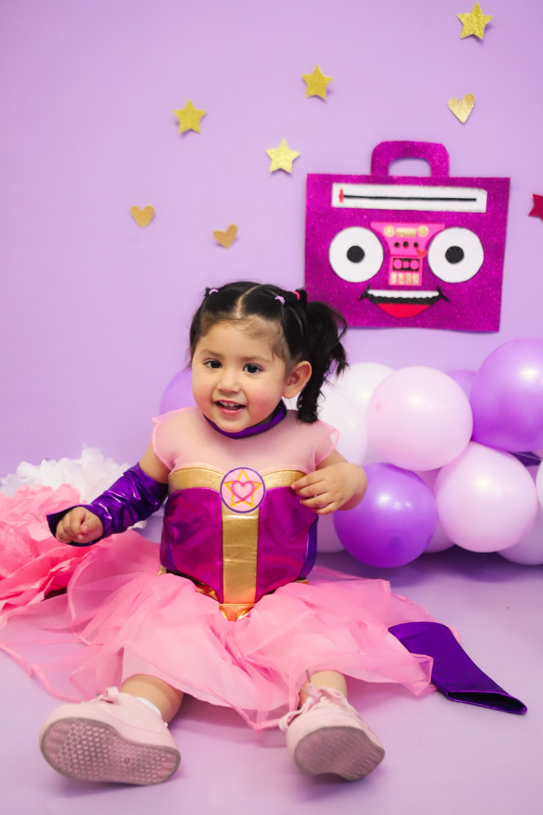 Niña disfrazada de princesa en un set morado con globos y estrellas.