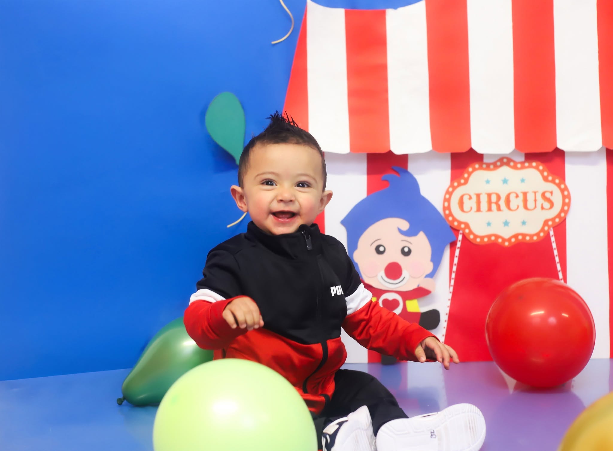 Bebé de un año sonriendo entre globos durante su sesión de Smash Cake.