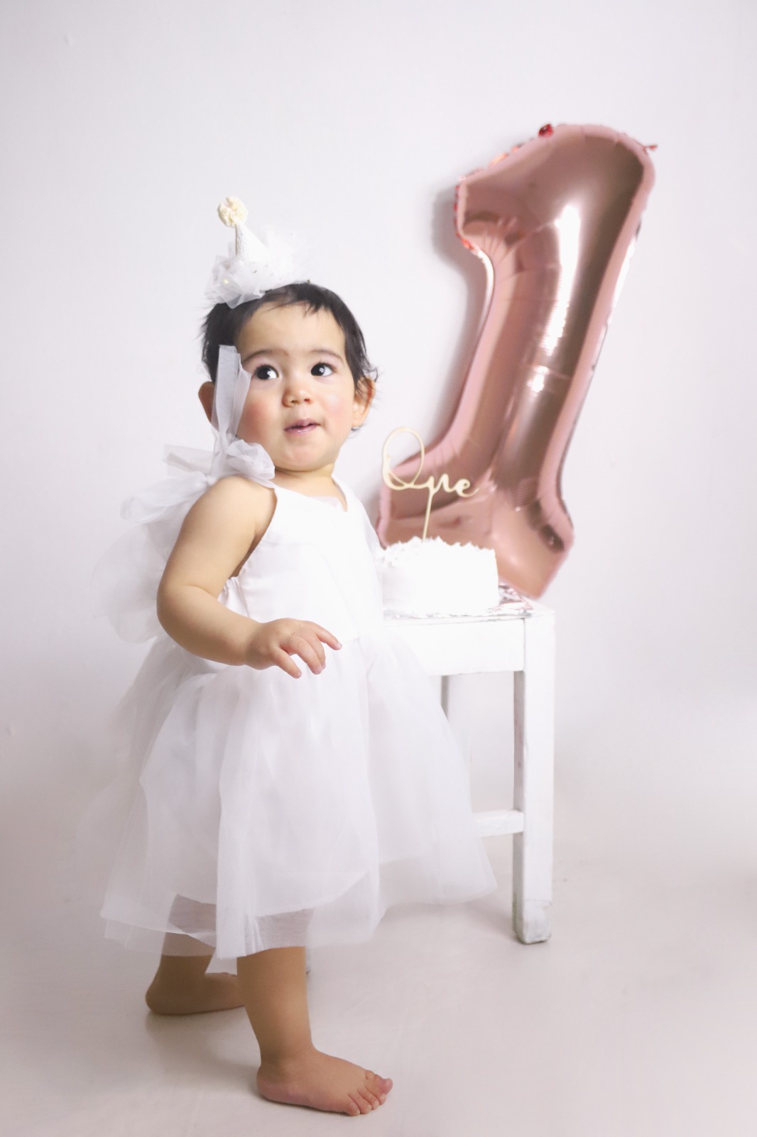 Bebé sonriendo junto a la decoración de su primer cumpleaños.